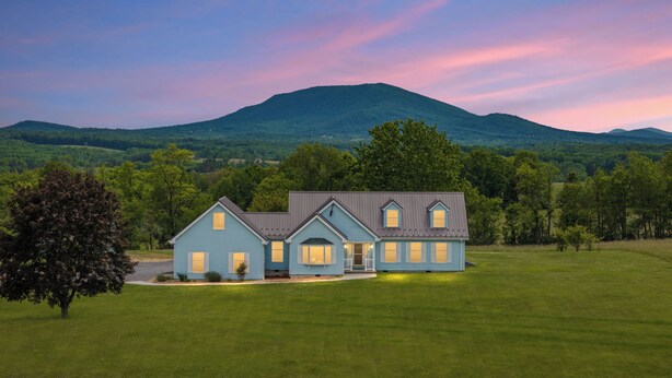 A two-story house with a front porch, a garage, and a large lawn.