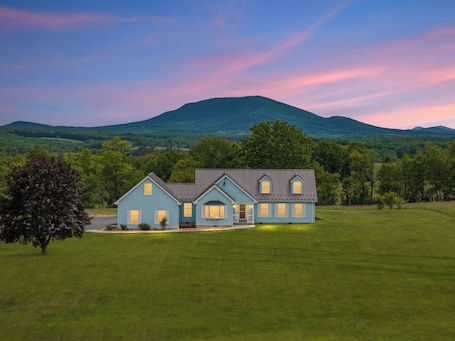 A two-story house with a front porch, a garage, and a large lawn.. NEW - Country Roads Cottage - Amish Living Reimagined in WV - HOT TUB