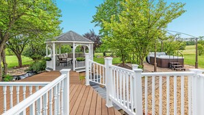A gazebo with outdoor seating, a hot tub, and a wooden deck with a white railing.