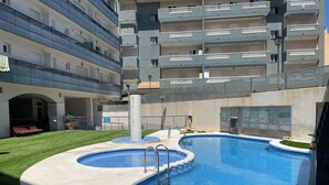 Una piscina con diseño circular, rodeada por una solana de concreto y una zona ajardinada.