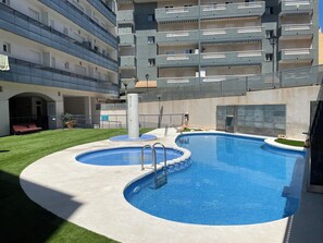 A swimming pool with a circular design, surrounded by a concrete deck and a grassy area. - Apartment very close to the beach and the subway station. (El Campello)