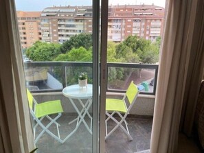 A balcony with a table and two chairs, overlooking a residential area with buildings and greenery. - Apartment very close to the beach and the subway station. (El Campello)
