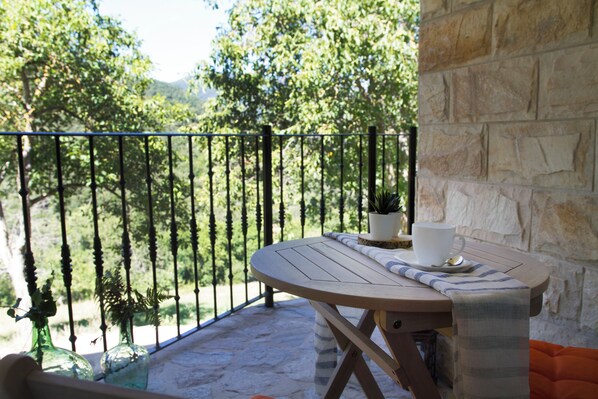 A balcony with a table, a potted plant, and a cup.
