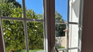 Ein Zimmer mit einem großen Fenster, einem Heizkörper und einer gestreiften Bettdecke.