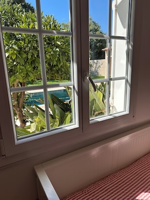 Ein Zimmer mit einem großen Fenster, einem Heizkörper und einer gestreiften Bettdecke.