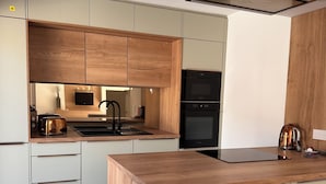 Eine moderne Küche mit Holzausstattung, einem eingebauten Backofen und einer großen Kochinsel mit Geschirrspüler.
