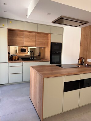 Eine moderne Küche mit Holzausstattung, einem eingebauten Backofen und einer großen Kochinsel mit Geschirrspüler.