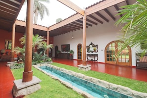 A courtyard with a swimming pool, palm trees, and a covered seating area. - w Spacious 12br Stay w Pool BBQ in Pachacamac (Pachacámac)