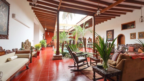A spacious living area with a red-tiled floor, wooden furniture, and a ceiling with exposed beams. - w Spacious 12br Stay w Pool BBQ in Pachacamac (Pachacámac)