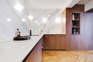 A modern kitchen with marble countertops, wooden cabinetry, and a herringbone floor pattern. - Elegant 125m² Apartment in Saint-Germain-des-Prés, Steps from Luxembourg Gardens (Paris)