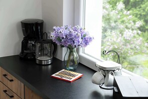 Eine Küchenarbeitsplatte mit Kaffeemaschine, Blumen in einer Vase und einem Teeservice.