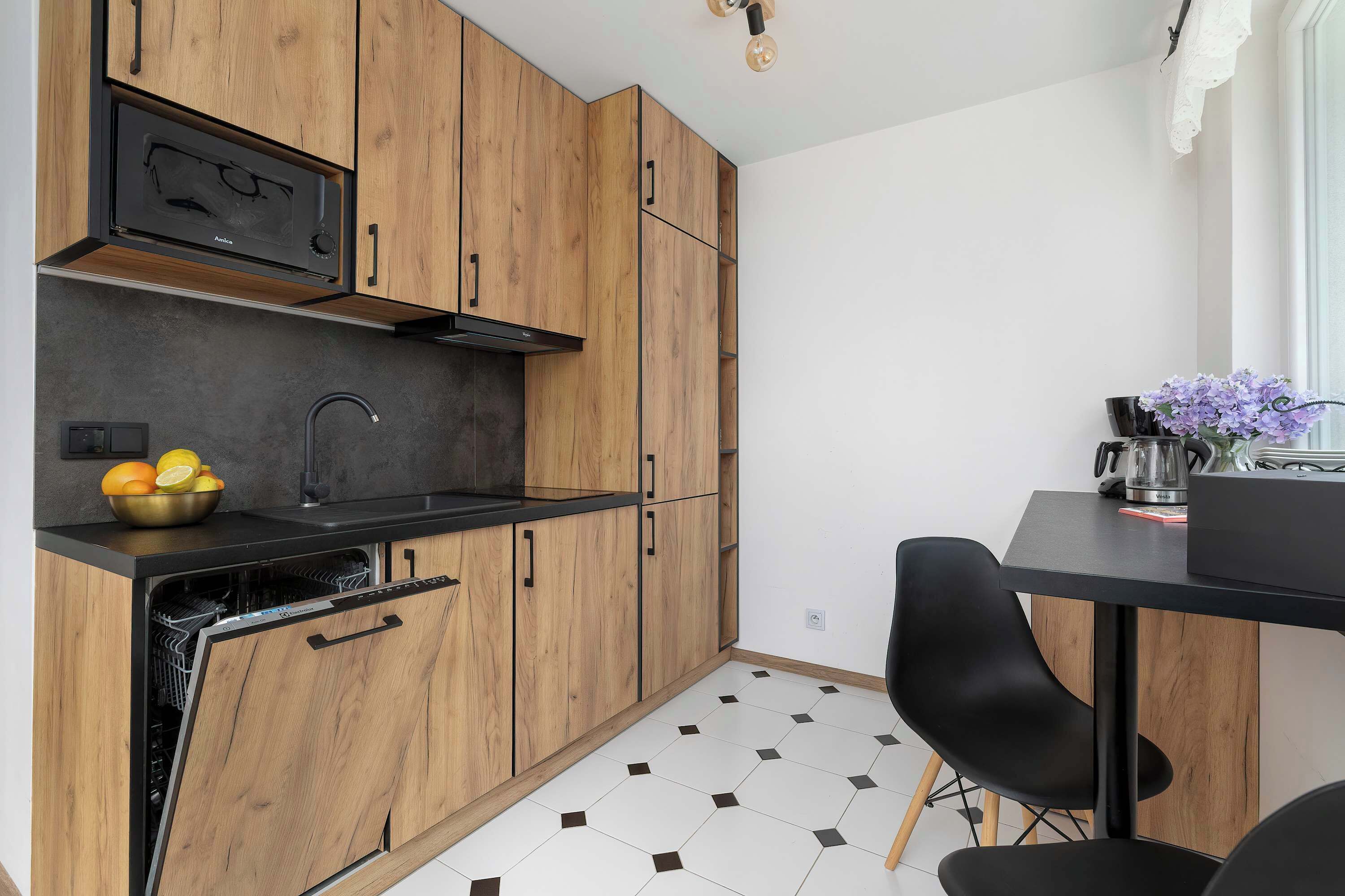 Eine moderne Küche mit Holzausstattung, einem Geschirrspüler und einer schwarzen Arbeitsplatte.