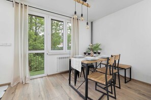 Ein Essbereich mit Tisch für vier Personen, einem Blumentopf und Blick ins Grüne.