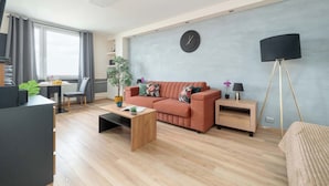 A modern living room with a sofa, coffee table, and a lamp. - Modern Studio on Piotrkowska Street City View (Łódź)