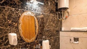 A bathroom with a marble wall, a pedestal sink, a toilet, and a hand dryer. - Hotel Shree Karni Palace (Beawar)