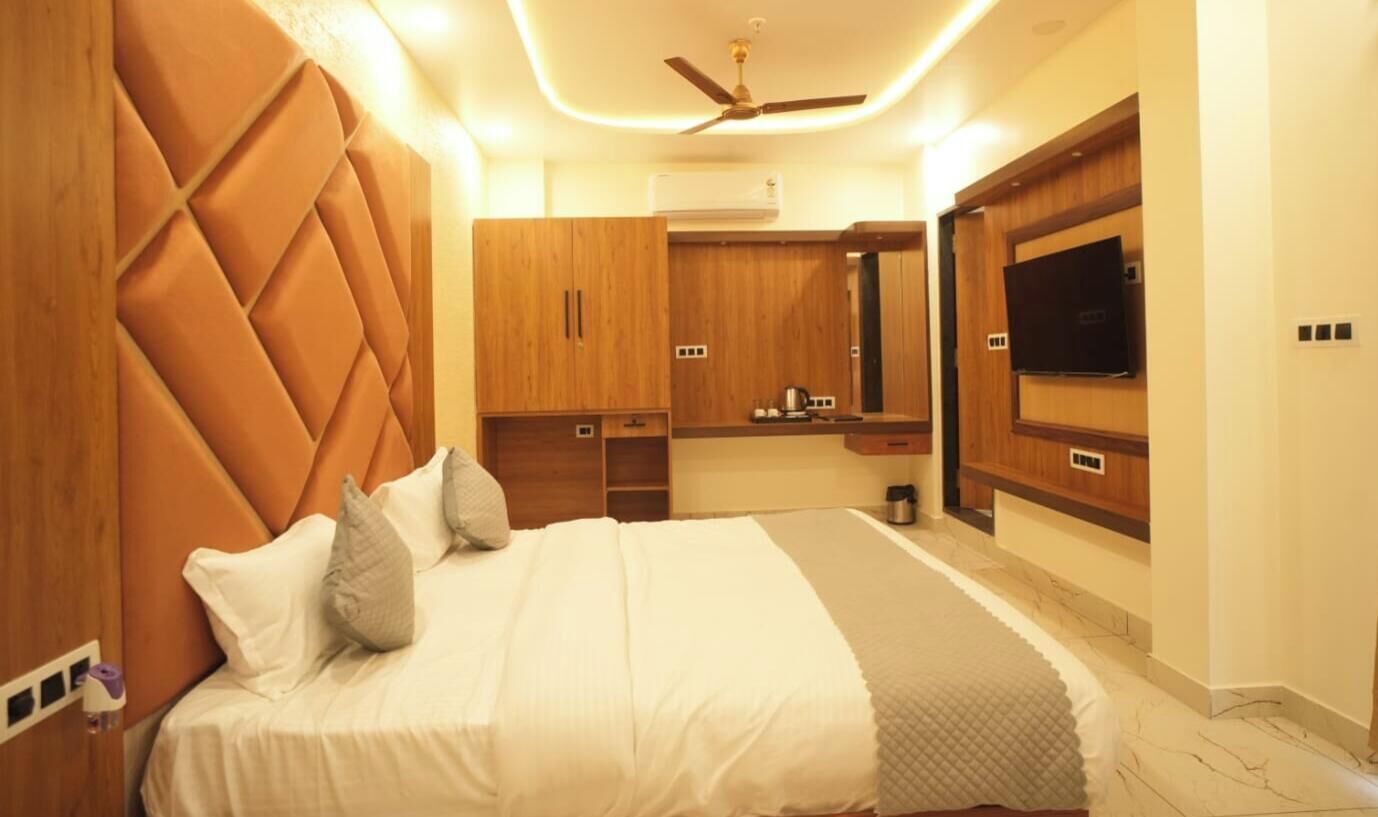 Een slaapkamer met een bed, een houten garderobe, een ingebouwde televisie en een plafondventilator.
