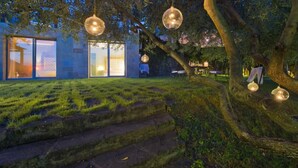 A modern building with large glass doors, a stone staircase, and hanging spherical lights.