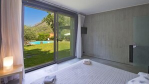 A bedroom with a large sliding glass door leading to a pool and garden.