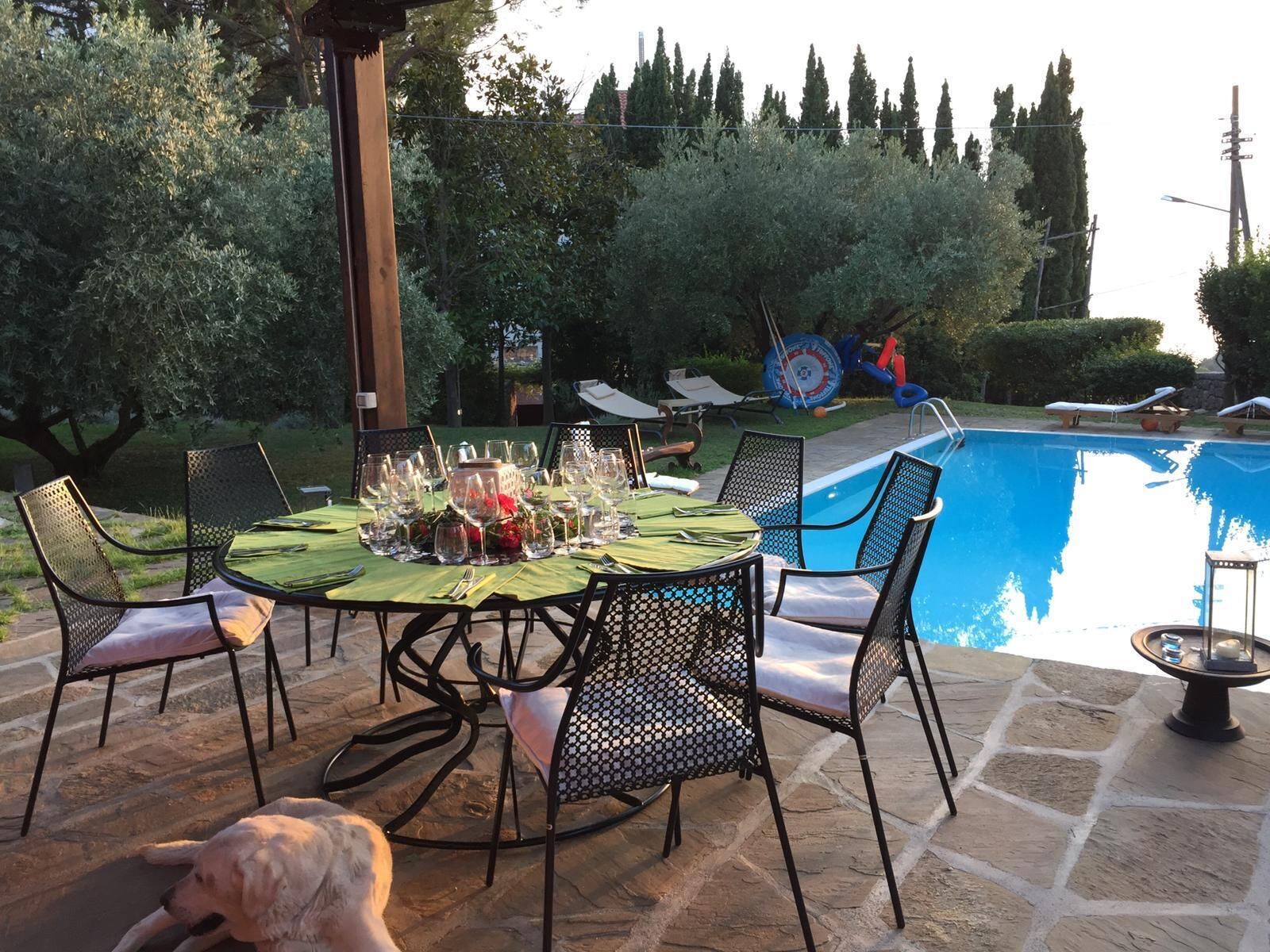 An outdoor dining area with a pool, stone flooring, and metal chairs.