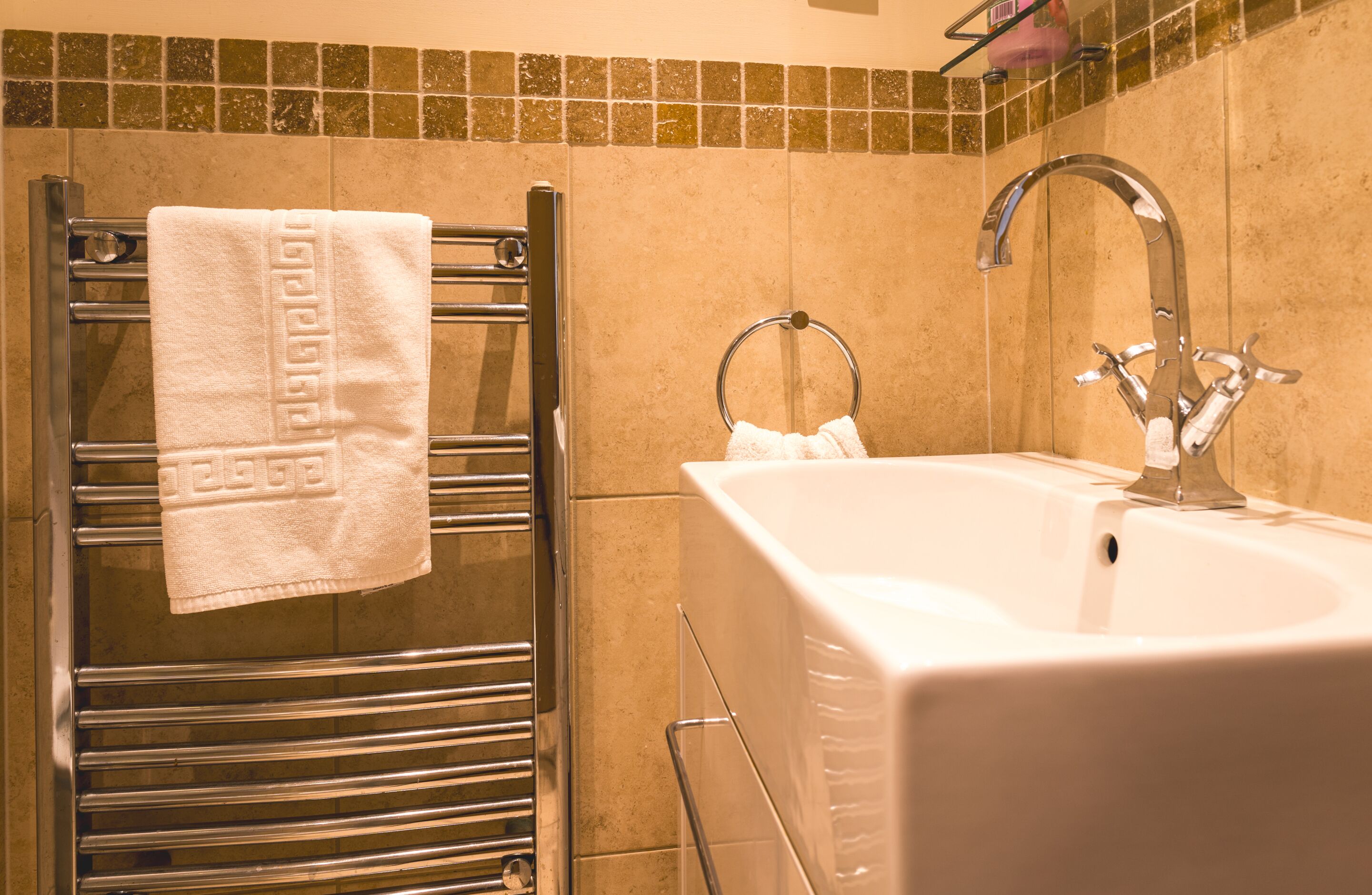 A bathroom with a towel rack, a sink, and a mirror.