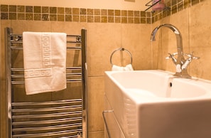 A bathroom with a towel rack, a sink, and a mirror.