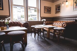En mysig pub med bekväma lädersitsar, träbord och en fin utsikt genom stora fönster.