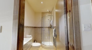 A bathroom with a glass shower enclosure, a toilet, and a sink.