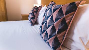 A neatly made bed with patterned pillows and a wooden headboard.