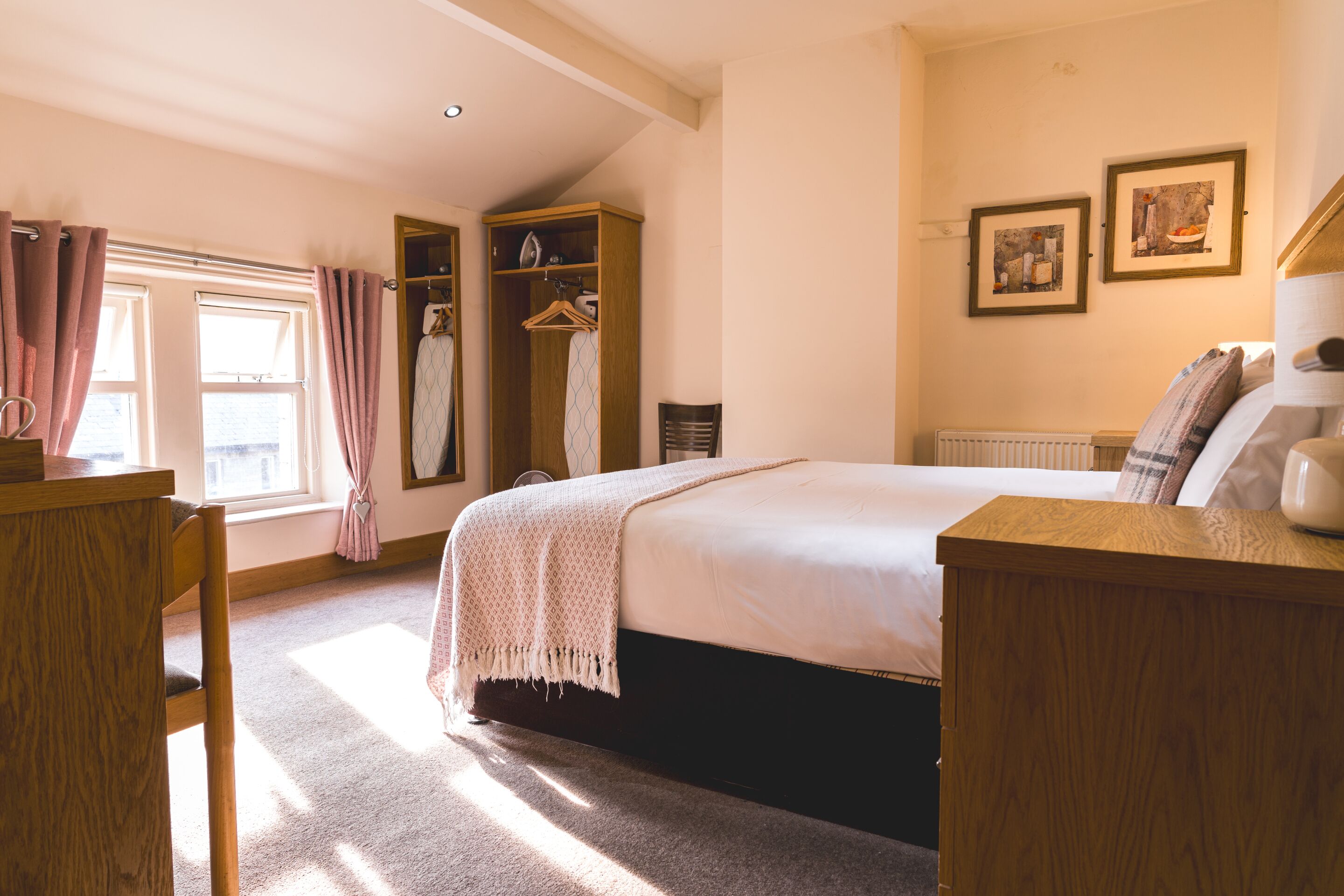 A bedroom with a bed, a wooden dresser, a wardrobe, and a radiator.