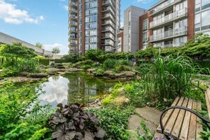 Ein Wohnhaus mit einem Gartenpond, umgeben von viel Grün und einer Holzbank.