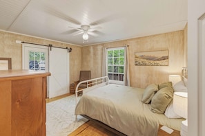 A bedroom with a bed, bedside lamps, a ceiling fan, a window, and a door. - Dog-friendly steps to Warwoman Dell in the Chattahoochee National Forest (Clayton)