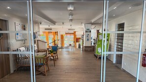 Um hall de hotel moderno com piso de madeira, áreas de estar e uma escada que leva aos andares superiores.