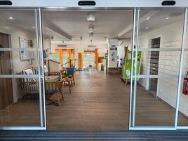 Un hall d’hôtel moderne avec un revêtement de sol en bois, des espaces de détente et un escalier menant aux étages supérieurs.