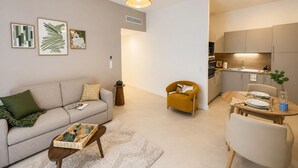 Uma sala de estar moderna com sofá, poltrona, mesa de centro e área de jantar com mesa posta para dois.