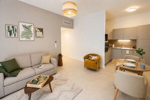 Un salon moderne comprenant un canapé, un fauteuil, une table basse et un coin repas avec une table mise pour deux personnes.