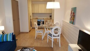 A compact living space with a dining area, kitchenette, and a TV.