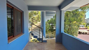 A spacious corridor with blue walls, a tiled floor, and a staircase leading to an outdoor area. - HotelStina (Rrashbull)