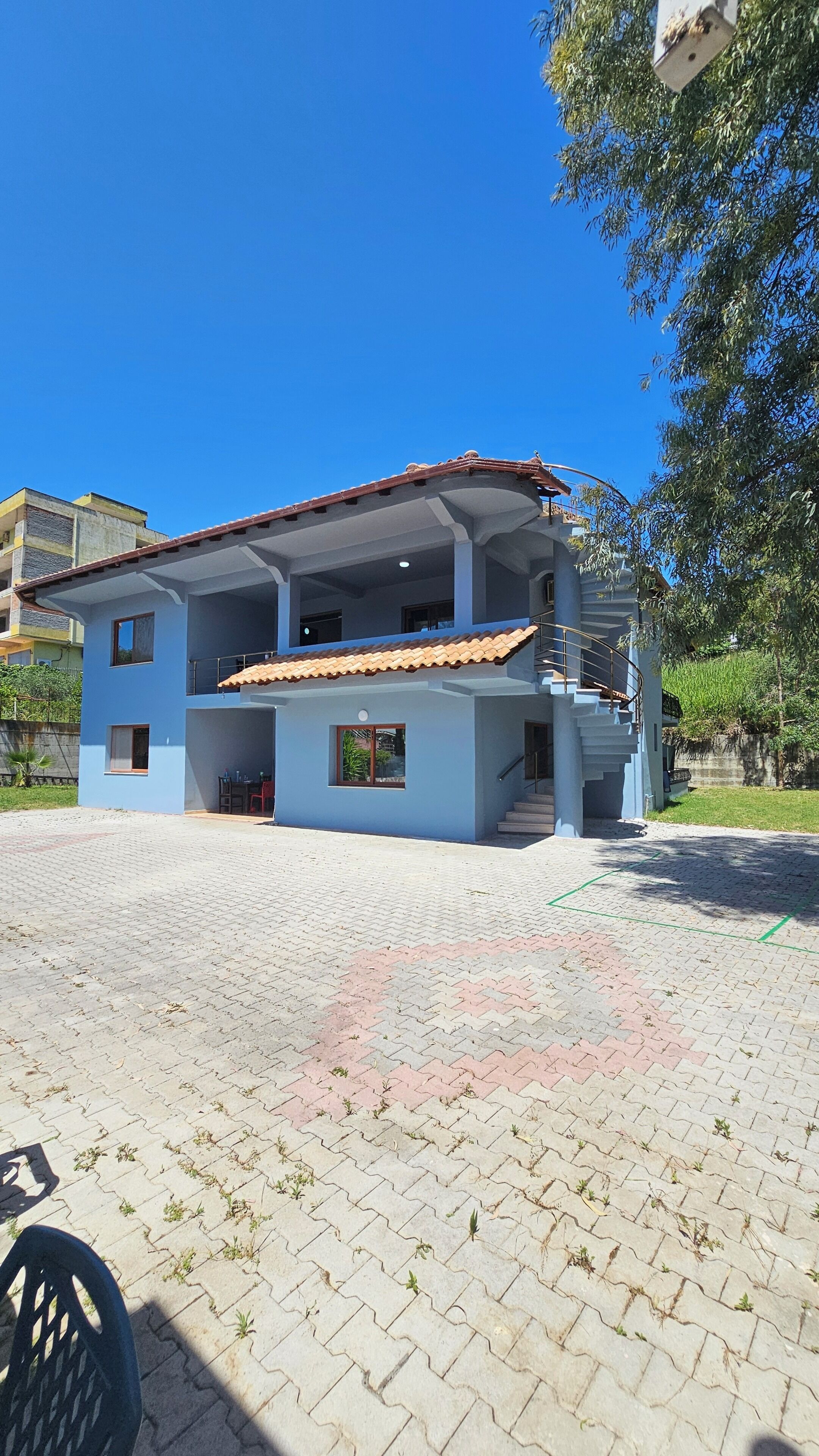 A two-story building with a tiled roof, a balcony, and a staircase leading to the upper floor.