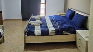 A bedroom with a bed, a nightstand, a dresser, an air conditioning unit, and a window with curtains. - HotelStina (Rrashbull)