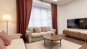 A modern living room with a sofa, a coffee table, a TV, and a window with curtains. - CENTRAL 16 by Kyosai (Bilbao)