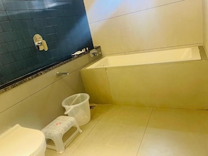 A bathroom with a bathtub, toilet, and a trash bin. - Casa Sevara (Vagator)