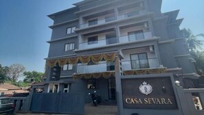 Um edifício de vários andares com entrada protegida por portão, uma placa com a inscrição 'CASA SEVARA' e céu claro.
