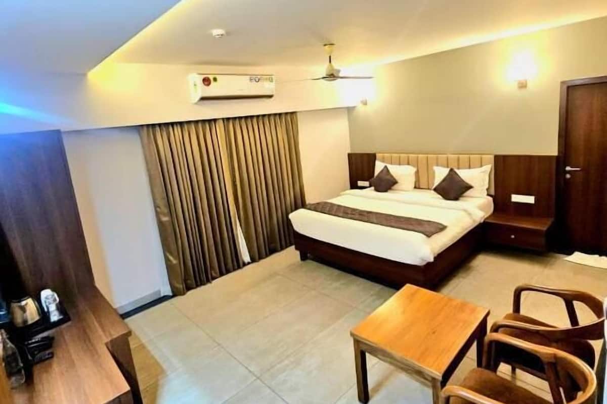 A hotel room with a bed, a desk, a chair, a table, and a ceiling fan.