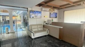 Um hall de entrada com balcão de recepção, um sofá e um painel de vidro.