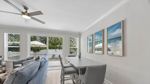A modern living room with a sofa, dining table, chairs, and a ceiling fan. - Beautiful 3BR 3BA Townhome~ Steps from the Beach! (Fernandina Beach)