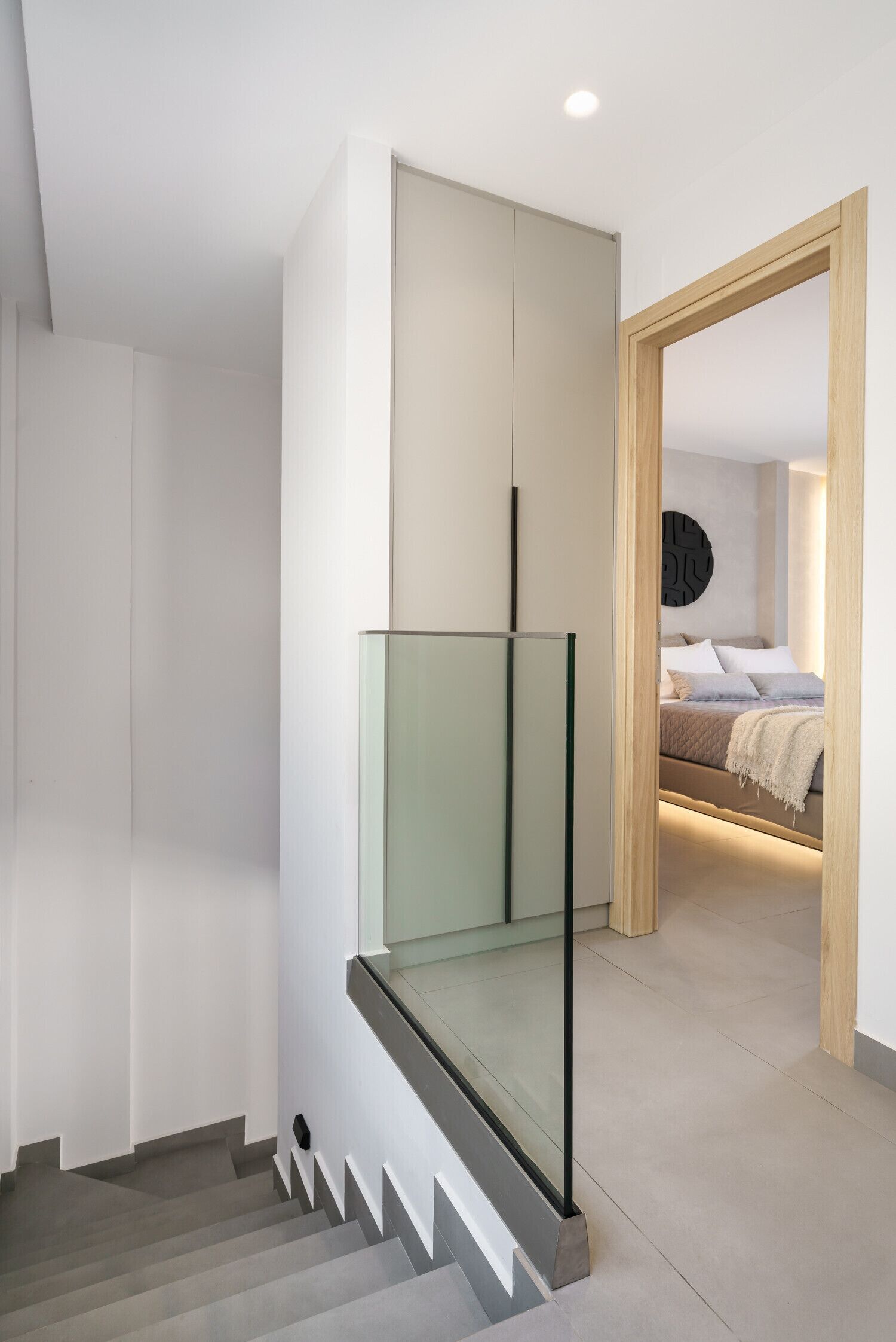 Un intérieur moderne avec un escalier, un lit doté d’une tête de lit et une œuvre d’art accrochée au mur.