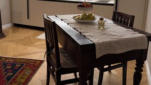 Una cocina moderna con una isla integrada, una mesa de comedor con sillas y una encimera con una tetera y una balanza.
