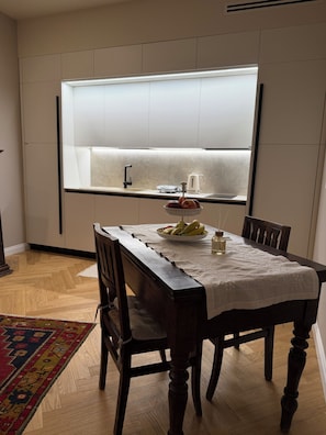 Una cocina moderna con una isla integrada, una mesa de comedor con sillas y una encimera con una tetera y una balanza.
