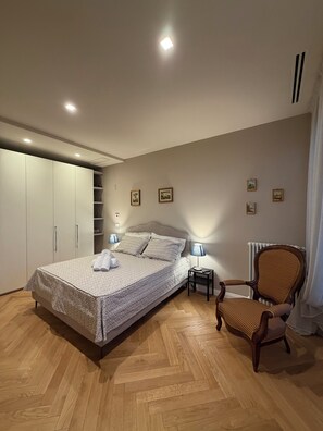 Un dormitorio con cama, una silla, un armario y un radiador.