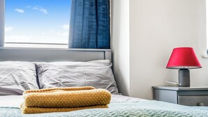 A bed with a green patterned bedspread, two pillows, and a yellow blanket. - Spacious 3BR Duplex | Sleeps 7 | 2 En-Suites | Secure Parking | 3 Balconies (Birmingham)